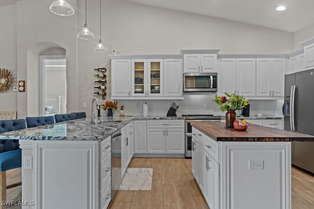 kitchen featuring appliances with stainless steel finishes, a kitchen bar, kitchen peninsula, sink, and butcher block counters