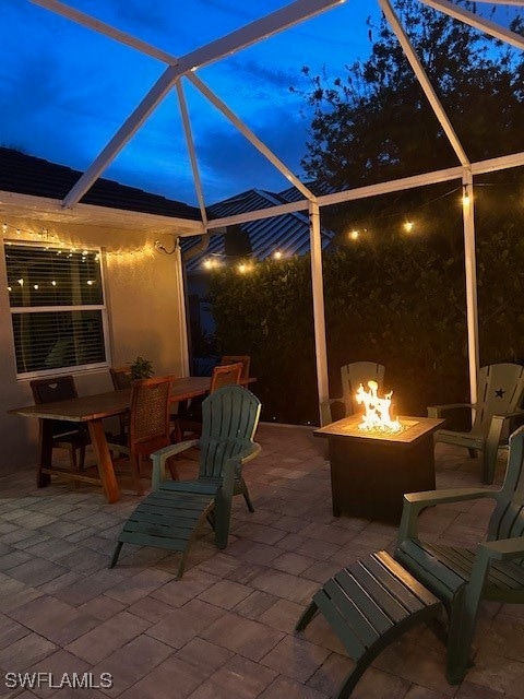 patio at twilight featuring an outdoor fire pit and a lanai