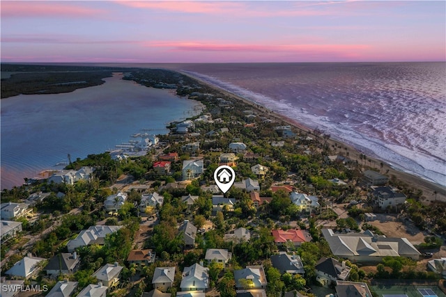 aerial view at dusk with a view of the beach and a water view