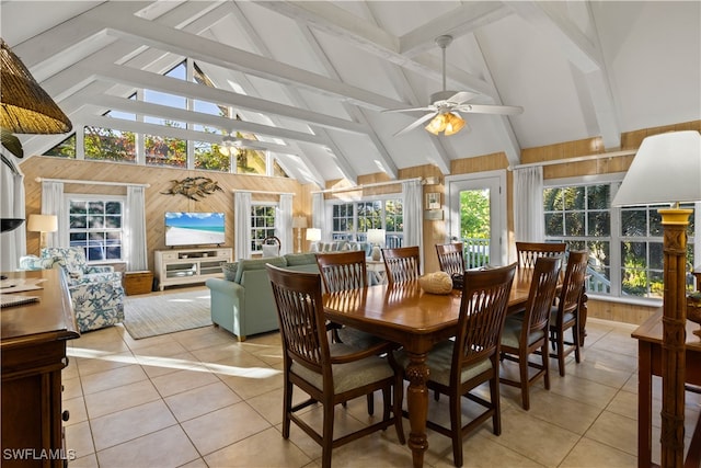 dining space featuring light tile patterned floors, high vaulted ceiling, ceiling fan, and wooden walls