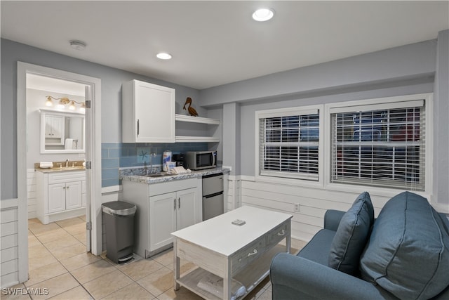 kitchen with appliances with stainless steel finishes, light tile patterned floors, white cabinetry, and sink