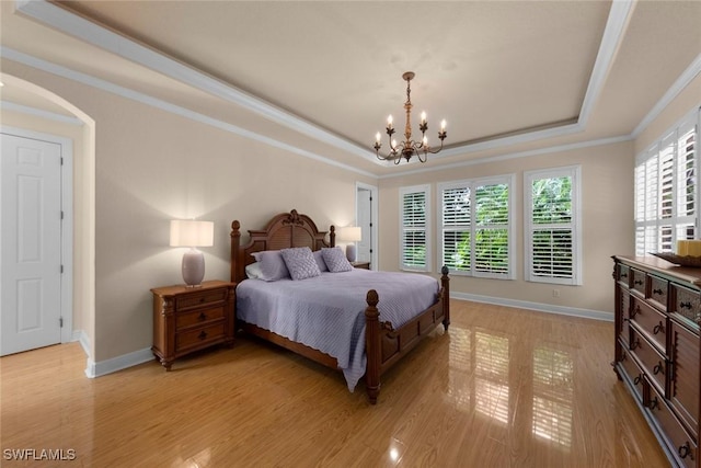 bedroom with a chandelier, light wood-type flooring, crown molding, and a tray ceiling