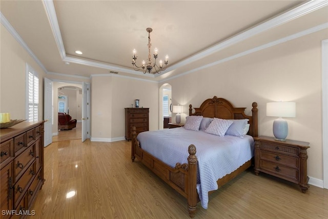 bedroom with a notable chandelier, light hardwood / wood-style floors, a raised ceiling, and ornamental molding