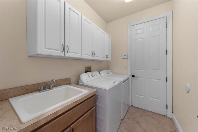 laundry area featuring washer and dryer, light tile patterned flooring, cabinets, and sink