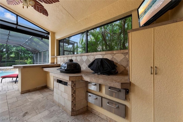 view of patio / terrace featuring glass enclosure, area for grilling, ceiling fan, and a grill