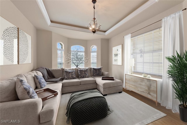 living room with hardwood / wood-style floors, a notable chandelier, and a tray ceiling