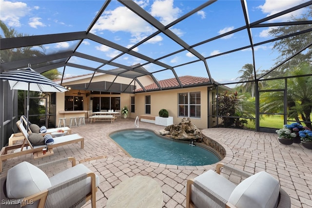 view of swimming pool featuring outdoor lounge area, glass enclosure, an outdoor bar, and a patio