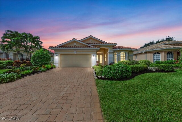 mediterranean / spanish-style house featuring a garage and a lawn