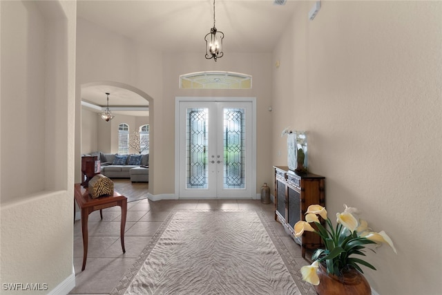 tiled foyer with french doors and a chandelier