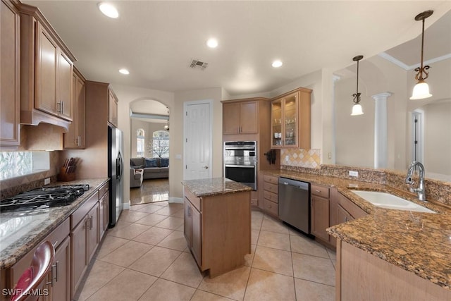 kitchen with sink, dark stone counters, pendant lighting, a kitchen island, and appliances with stainless steel finishes