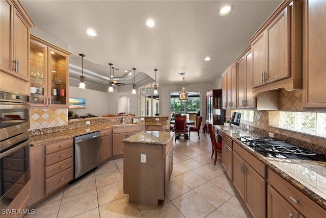 kitchen featuring a center island, sink, appliances with stainless steel finishes, decorative light fixtures, and kitchen peninsula