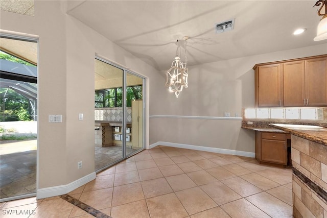 kitchen with light stone counters, light tile patterned flooring, and hanging light fixtures