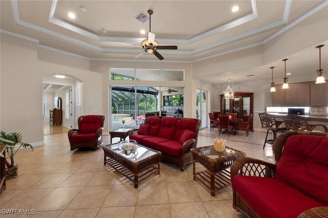 tiled living room featuring a tray ceiling, crown molding, a high ceiling, and ceiling fan with notable chandelier