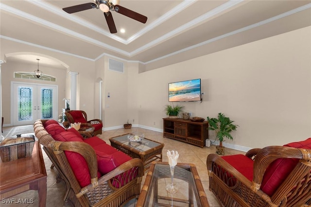 tiled living room with ornate columns, ceiling fan, french doors, a raised ceiling, and ornamental molding