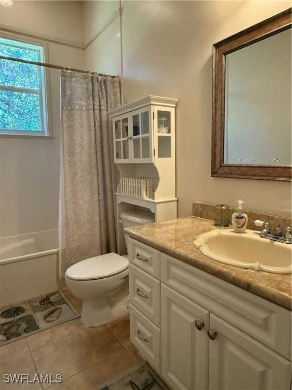 full bathroom with tile patterned floors, shower / tub combo with curtain, vanity, and toilet