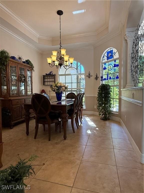 dining area with a tray ceiling, an inviting chandelier, crown molding, and light tile patterned flooring