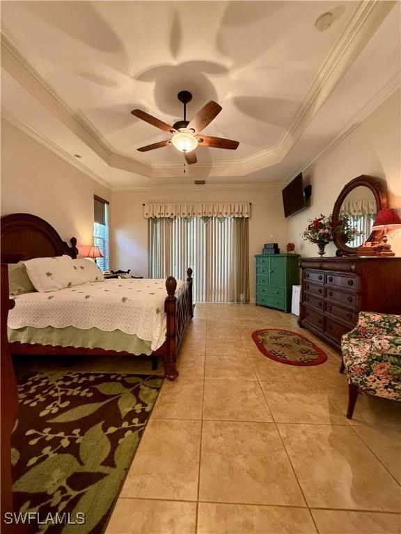 bedroom with tile patterned floors, ceiling fan, and a raised ceiling