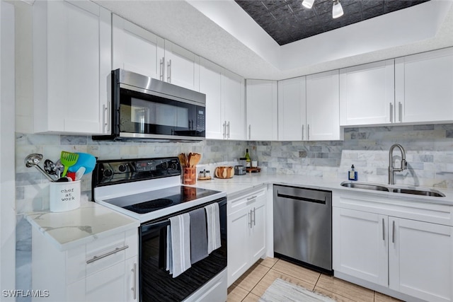 kitchen with light tile patterned flooring, sink, white cabinetry, stainless steel appliances, and decorative backsplash