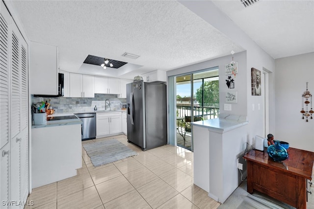 kitchen with decorative backsplash, stainless steel appliances, white cabinets, and light tile patterned flooring