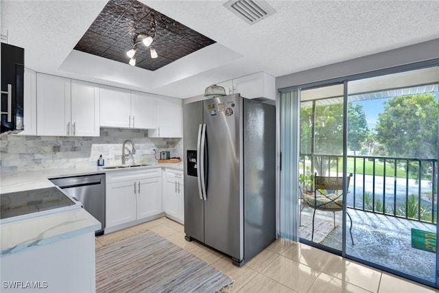 kitchen with sink, white cabinetry, stainless steel appliances, a raised ceiling, and light tile patterned floors