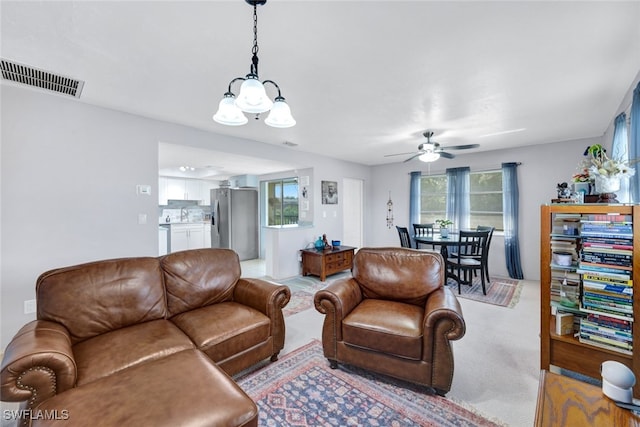 living room featuring ceiling fan with notable chandelier and light carpet