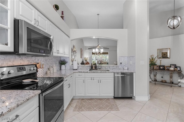 kitchen with appliances with stainless steel finishes, sink, decorative light fixtures, white cabinets, and light tile patterned floors