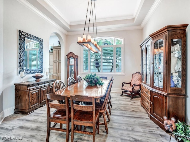 dining area with ornamental molding, a tray ceiling, light hardwood / wood-style floors, and a notable chandelier