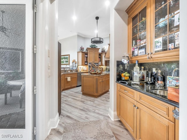 bar with hanging light fixtures, dark stone countertops, dishwasher, light hardwood / wood-style flooring, and sink