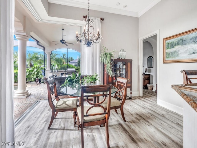 dining space featuring ceiling fan with notable chandelier, decorative columns, crown molding, and light hardwood / wood-style flooring