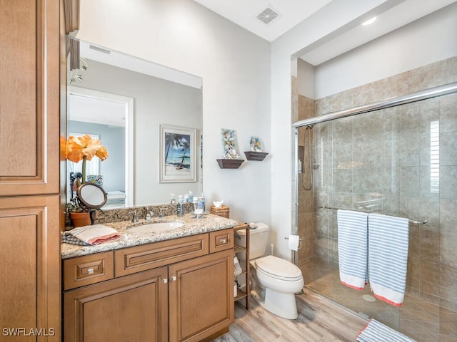 bathroom featuring hardwood / wood-style floors, vanity, toilet, and a shower with shower door