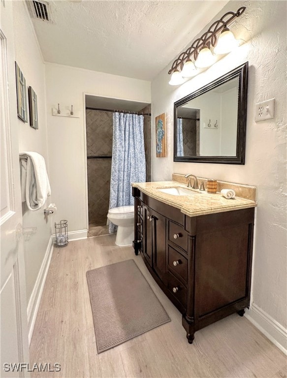 bathroom with toilet, wood-type flooring, curtained shower, vanity, and a textured ceiling