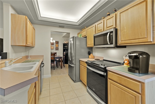 kitchen with light tile patterned floors, stainless steel appliances, a tray ceiling, light brown cabinetry, and sink