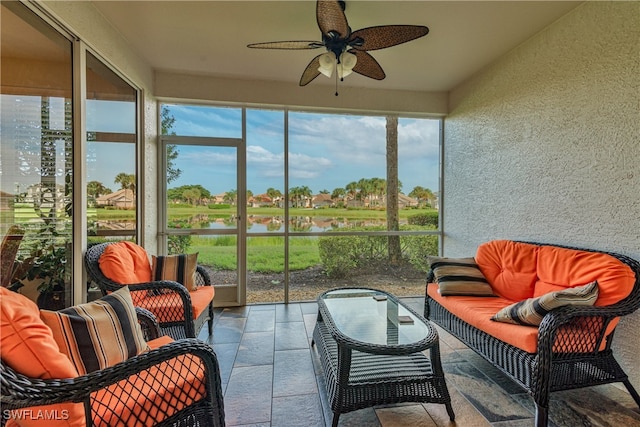 sunroom featuring ceiling fan and a water view