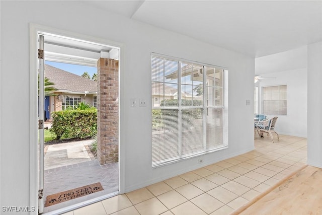 doorway featuring light tile patterned flooring and ceiling fan