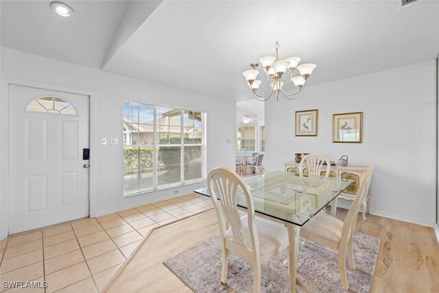 tiled dining room with vaulted ceiling and a chandelier