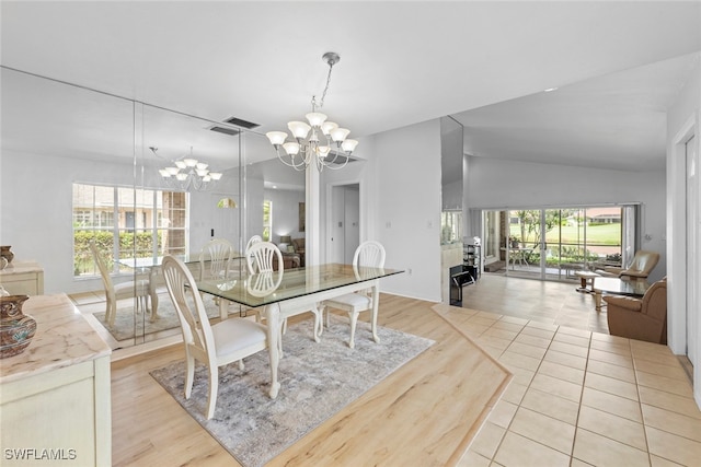 dining area with lofted ceiling, an inviting chandelier, a wealth of natural light, and light hardwood / wood-style flooring