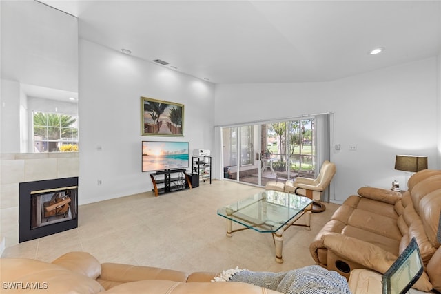 living room with high vaulted ceiling and a tiled fireplace