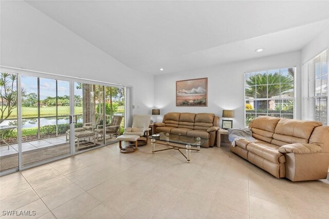 living room with a high ceiling, a water view, and light tile patterned floors