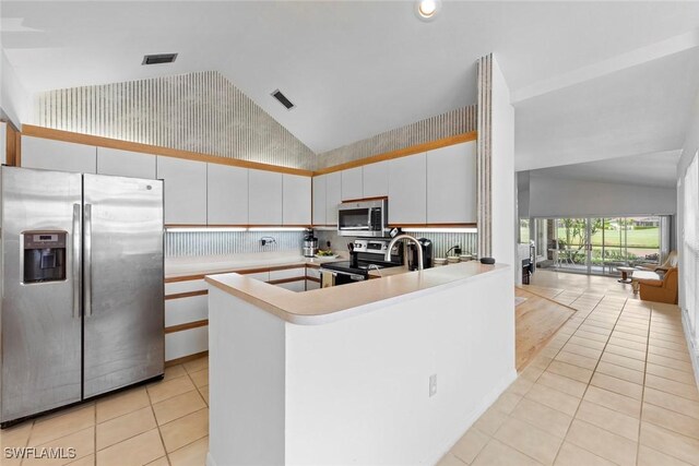 kitchen featuring stainless steel appliances, white cabinetry, tasteful backsplash, light tile patterned floors, and kitchen peninsula