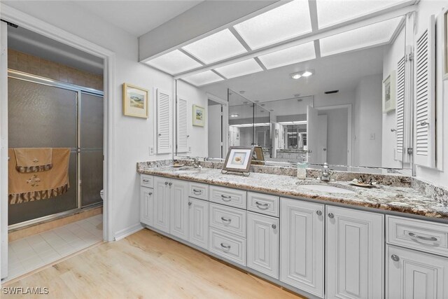 bathroom with wood-type flooring, an enclosed shower, vanity, and toilet