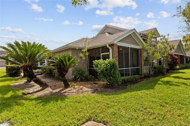 rear view of house featuring a lawn and a sunroom