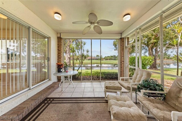 sunroom / solarium with ceiling fan and a water view