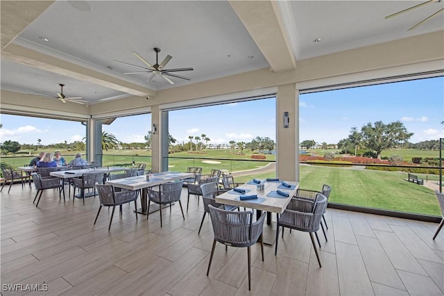 sunroom / solarium featuring beam ceiling and ceiling fan