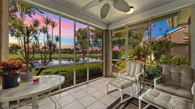 sunroom / solarium with ceiling fan and a water view