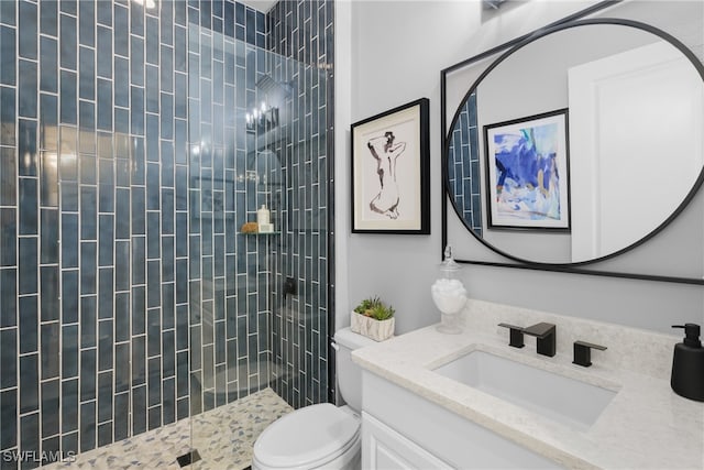 bathroom featuring vanity, a tile shower, and toilet