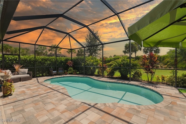 pool at dusk with a patio area and a lanai