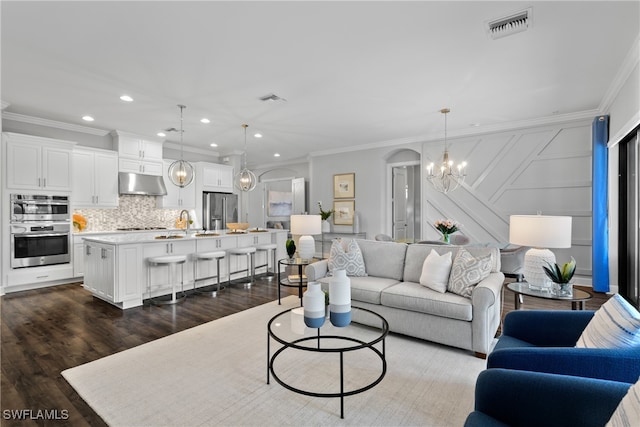 living room with ornamental molding, a chandelier, dark wood-type flooring, and sink