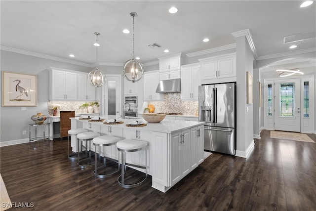 kitchen featuring dark hardwood / wood-style flooring, white cabinetry, a kitchen island with sink, decorative light fixtures, and stainless steel appliances