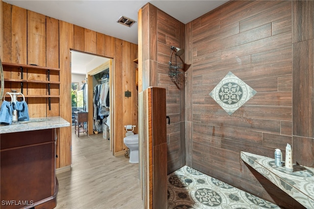 interior space with walk in shower, hardwood / wood-style floors, wood walls, and toilet