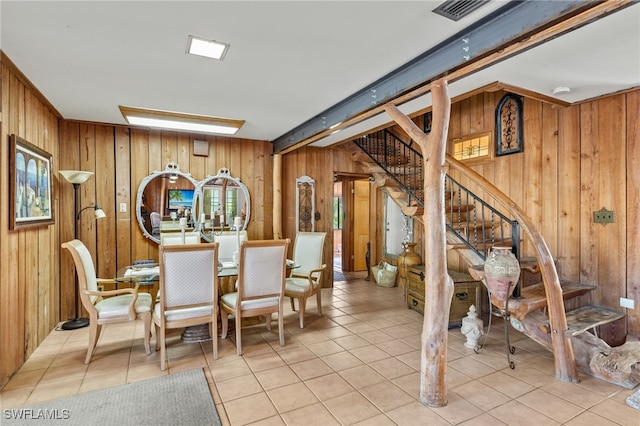 dining area featuring light tile patterned flooring and wood walls